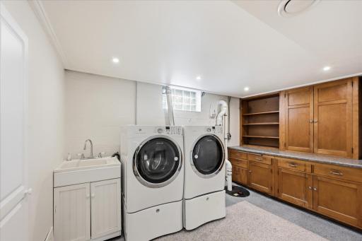 Spacious laundry room with a sink, plenty og storage and folding tables and a cedar closet.