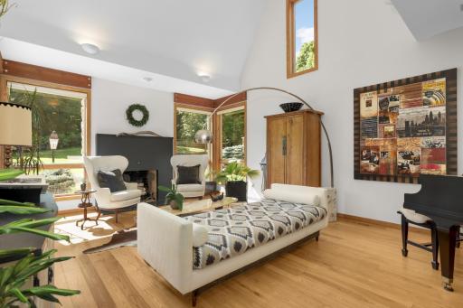 Vaulted living room with beautiful fireplace framed by floor to ceiling windows.