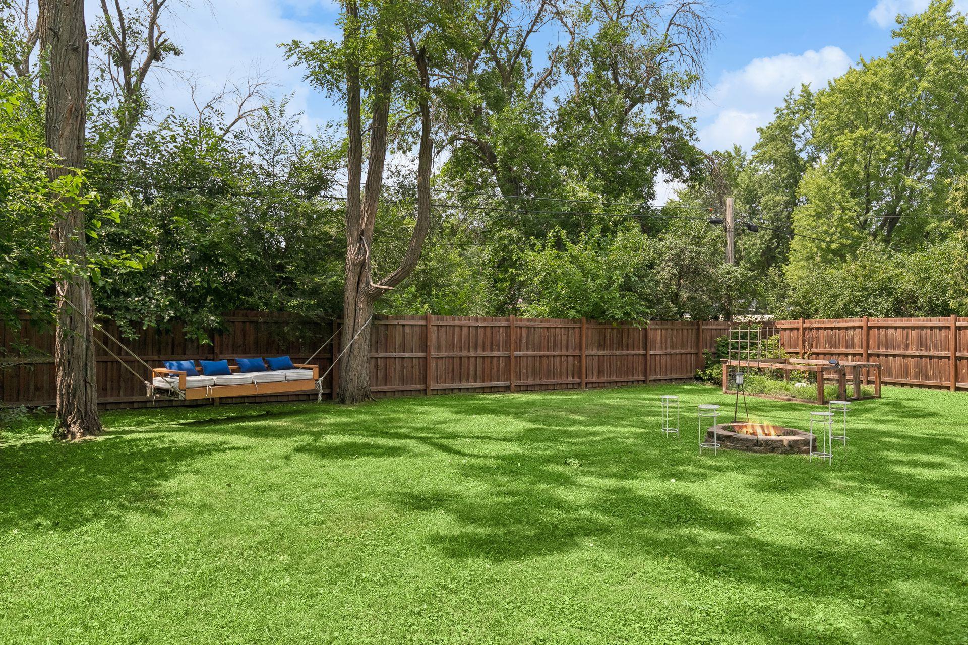 Room to roam — a wide, fenced backyard lawn shaded by mature trees.