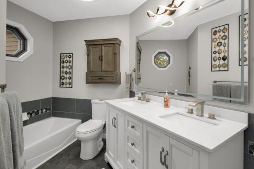 Fully updated bathroom with a relaxing tub, updated lighting, large double sink vanity, and a custom tiled shower with a luxury shower head.
