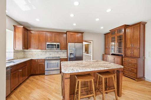 Kitchen features hardwood floors, stainless steal appliances, buffet with glass doors, kitchen desk, and window