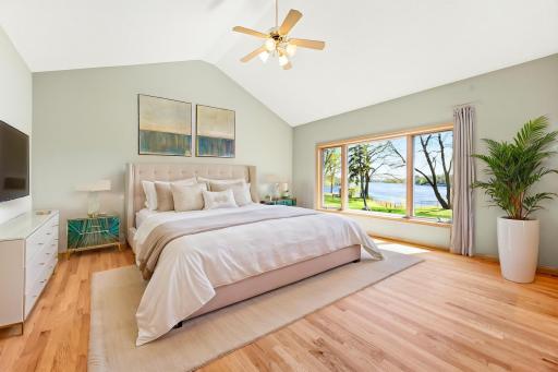 Spacious primary suite with vaulted ceilings and hardwood floors. Photo is virtually staged.