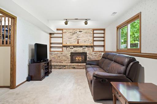 The lower level of the home includes this large family room with the gorgeous gas burning, brick fireplace with built in shelving to show case all your favorite things. The large window lets in tons of sunlight.