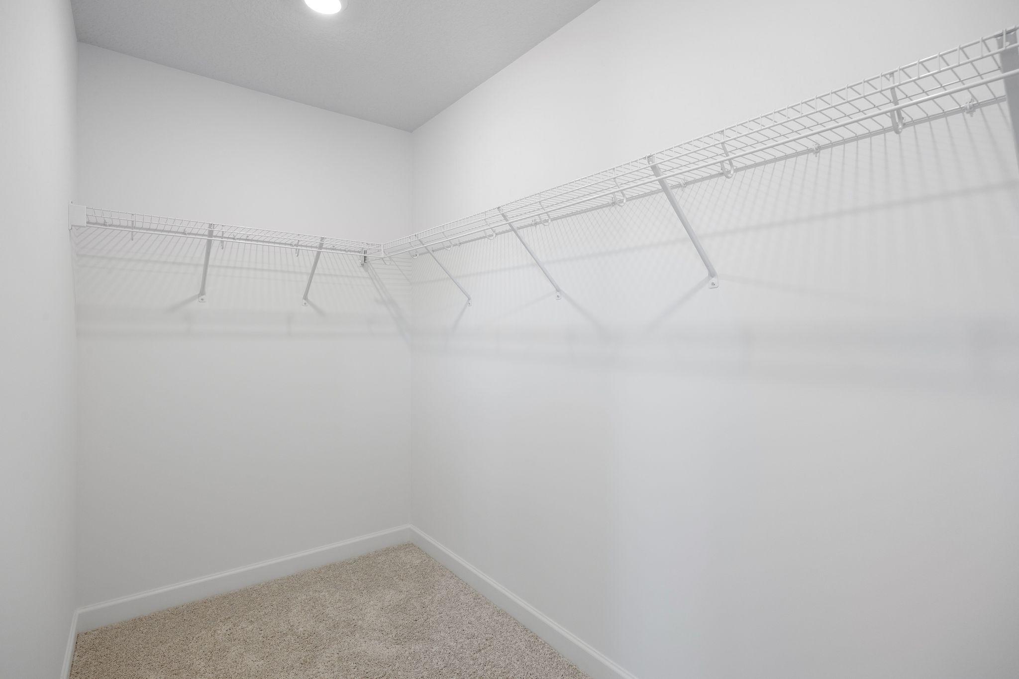 A large walk-in closet with mesh-wire shelving provides abundant room to store wardrobes, shoes, accessories and much more