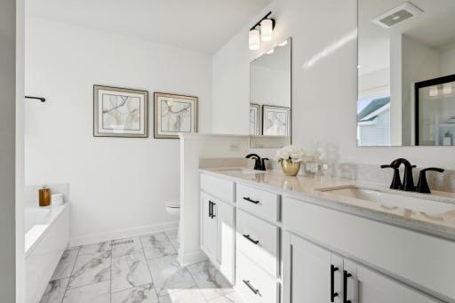 (Photo of a decorated model, actual homes finishes will vary) The private primary ensuite bath offers a wonderful luxury height double vanity with a quartz counter top, a soaking tub and separate shower.