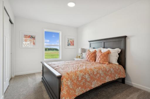 (Photo of a decorated model, actual homes finishes will vary) One of three generously sized upper level secondary bedrooms with spacious closets.