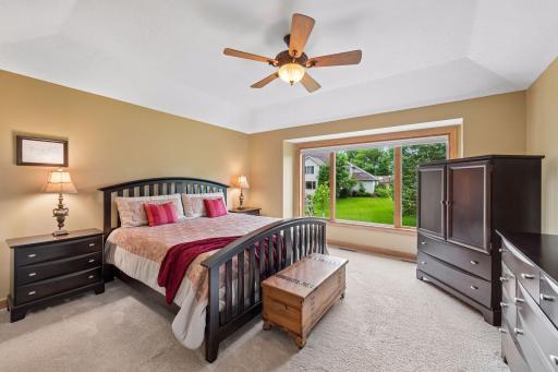 Relaxing upper level primary suite with large picture window, vaulted tray ceiling, and peaceful backyard views.
