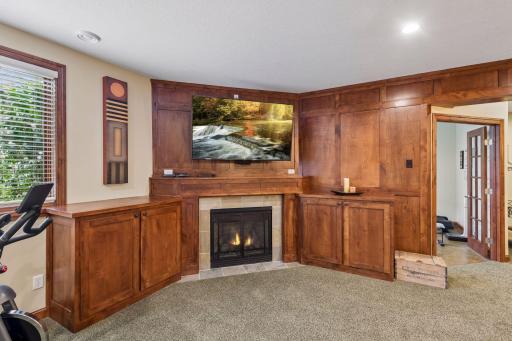 Beautiful custom woodwork surround the fireplace and provide exceptional storage, creating a comfortable space to relax after a workout in the nearby exercise room