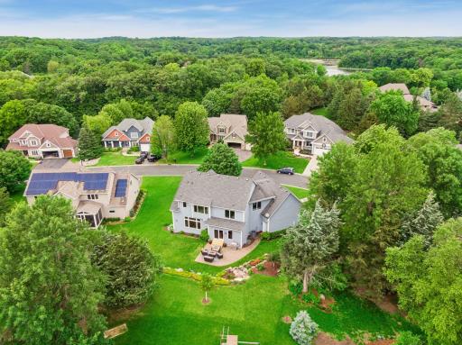 The aerial view highlights the generous lot, spacious backyard, established landscaping and picturesque neighborhood setting surrounded by nature.