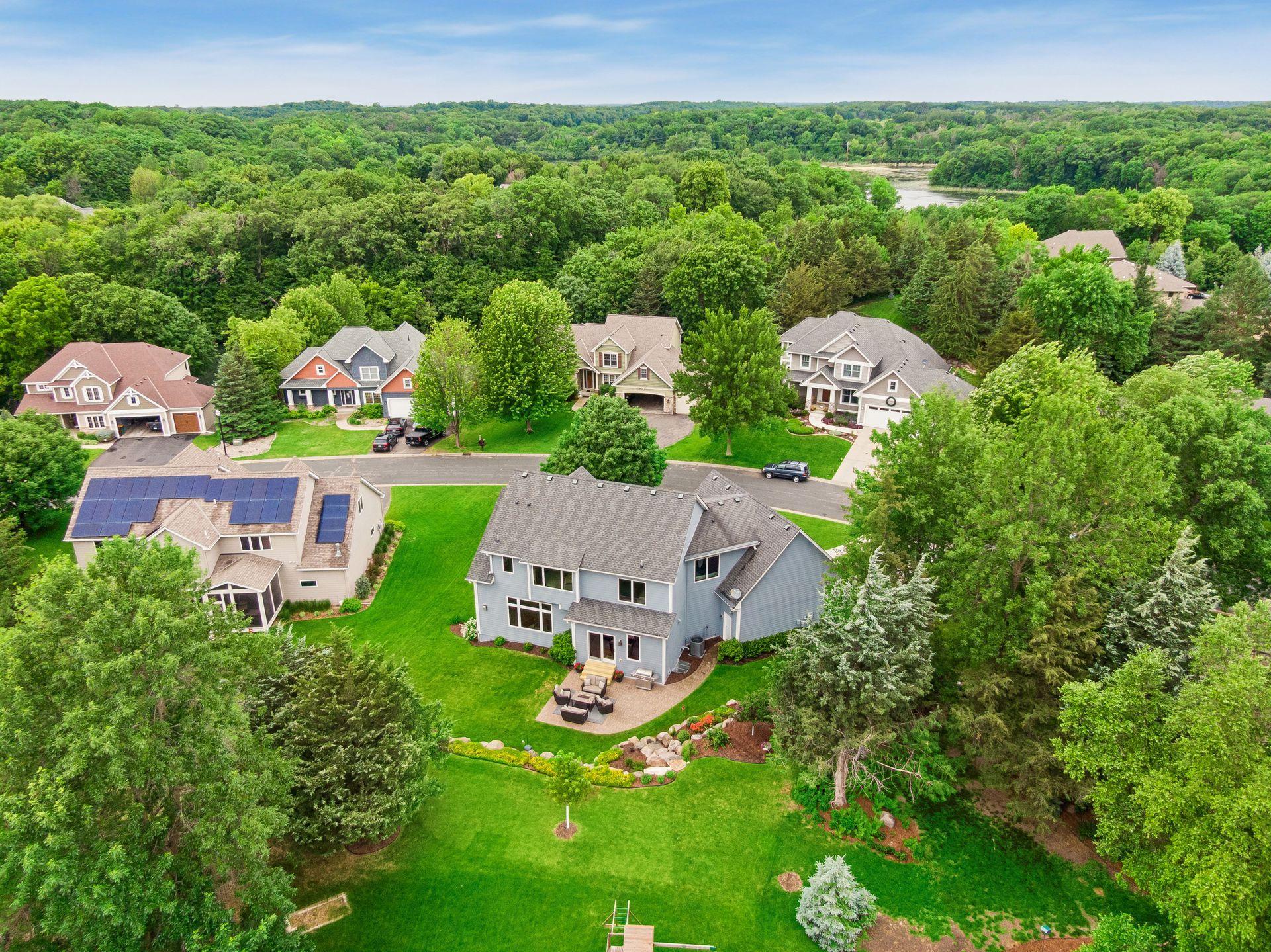 The aerial view highlights the generous lot, spacious backyard, established landscaping and picturesque neighborhood setting surrounded by nature.