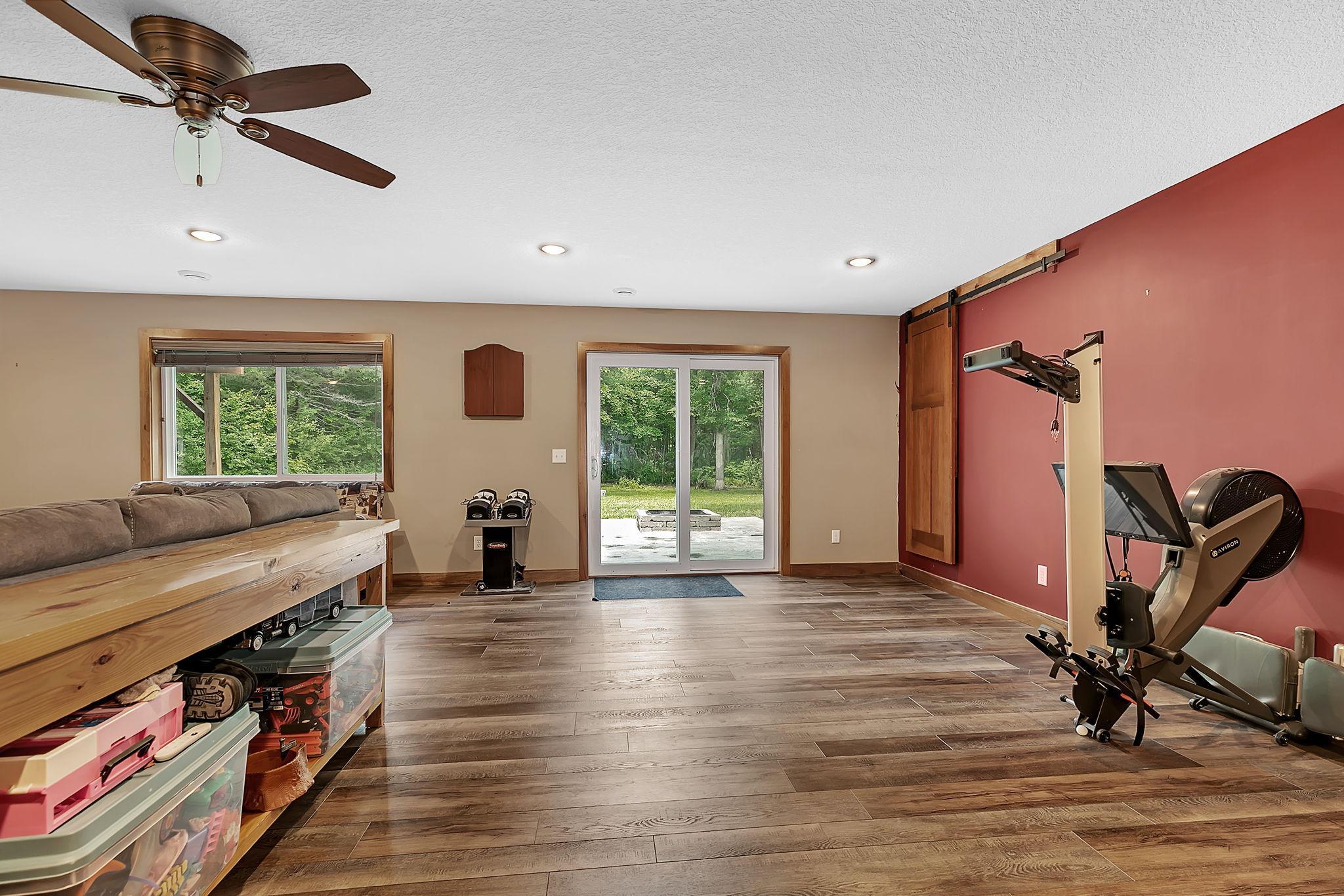 The lower-level recreation room offers flexibility for entertaining, fitness, games, or relaxing. A wood sliding door opens to the expansive storage area beneath the bonus room addition.