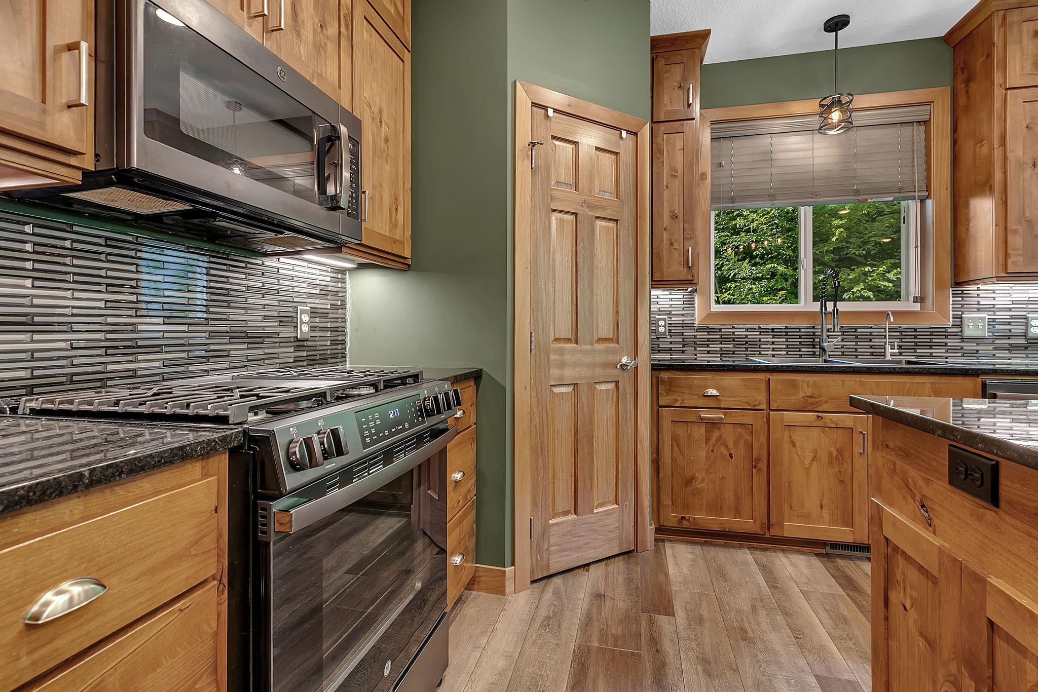 The kitchen is equipped with sleek appliances, a gas range for precision cooking, and a large window above the sink that fills the space with natural light while offering peaceful yard views.