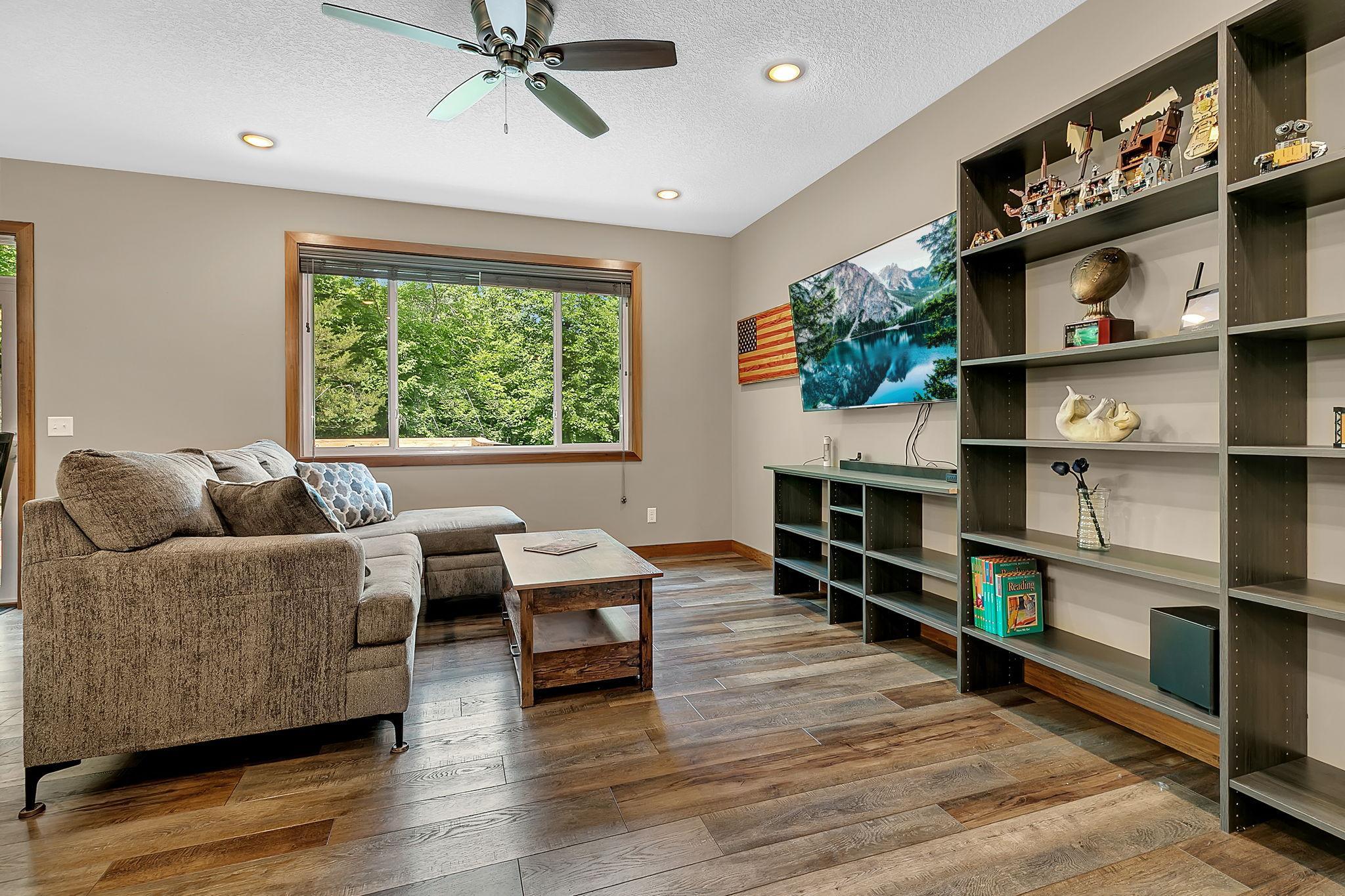 A spacious family room with expansive windows overlooking the private wooded setting, offering the perfect place to unwind, entertain, or gather with family and friends.