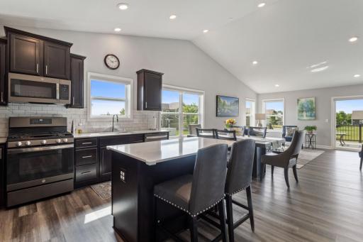 Open airy floor plan with the kitchen showing off many cabinets, vinyl plank flooring, a center island and stainless appliances