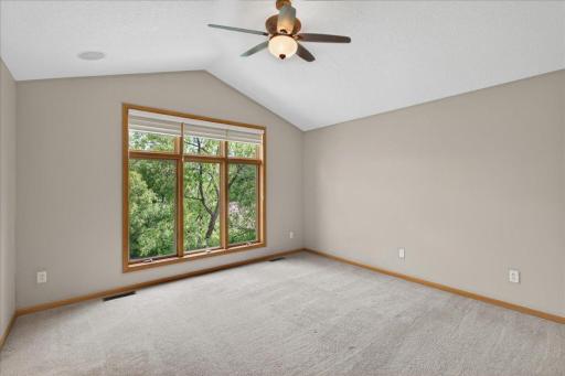 primary suite features vaulted ceilings and dramatic floor to ceiling windows overlooking the backyard