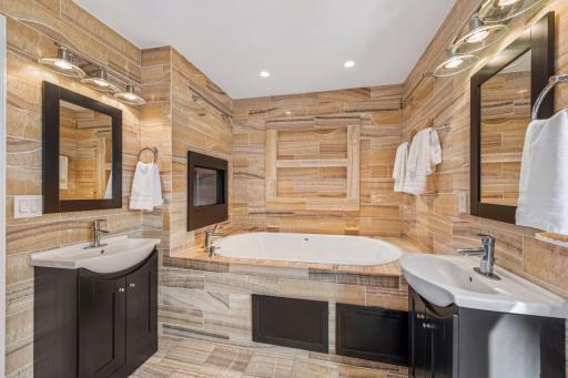 Spa-like ensuite bathroom with heated floors, fireplace, soaking tub and two sinks.