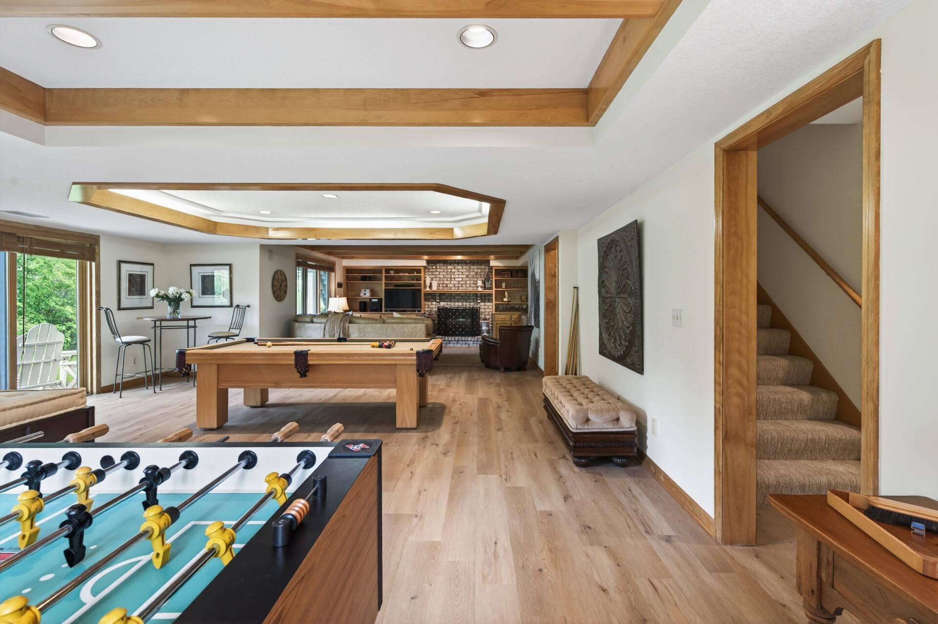 The walkout lower level is designed for gathering and fun, anchored by an incredible amusement room with maplebeamed ceilings, custom media built-ins, wet bar, brick-surround gas fireplace, and dedicated game area with included pool table.