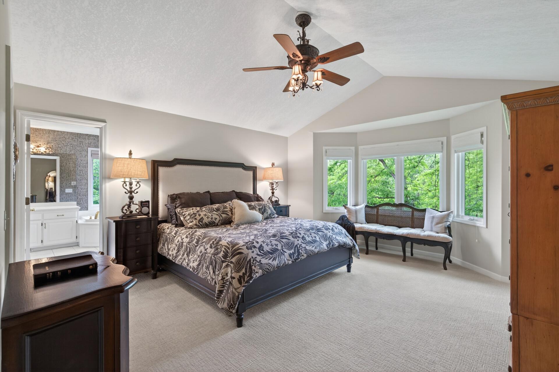 The primary suite feels like a private retreat, complete with a vaulted ceiling, bay window, custom-organized walk-in closet