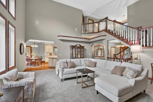 A stunning two-story living room filled with natural light creates an open, airy feel and serves as the heart of the home.