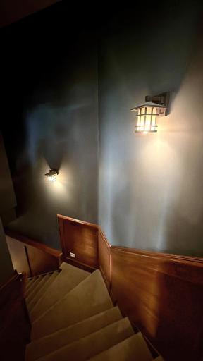Step into the secret passage! This lit stairwell leads to the lower level. A right turn takes you to the fully equipped workshop, while a left leads through a hidden wall door into the family room.