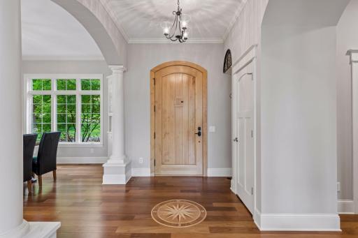 Unmatched craftsmanship in the foyer: solid Brazilian walnut floors with a custom compass inlay, an oversized 3'6" custom front door with mini door peephole, a guest closet, and a built-in coat rack nook.