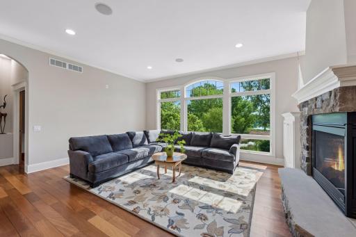 The formal living room includes a wall of windows overlooking the beautiful backyard and lake. It features a 3-sided gas fireplace, built-in entertainment center, crown molding, gorgeous wood floors, recessed lights and surround sound.