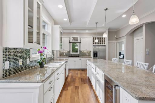 The massive granite island seats 4 and features a Viking beverage fridge and pull-out storage. Surrounded by premium Viking appliances, a sleek glass tile backsplash, abundant cabinets, and a built-in wine rack.