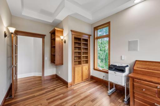 DON'T MISS THE SECRET STAIRCASE! A true hidden gem! This custom office bookcase features a secret door that opens to the lower-level entertainment room. Just pull the wooden "V" on the shelf to reveal the home's most unique, fun feature.