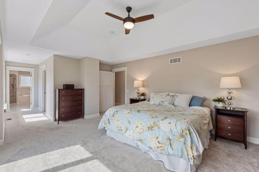 Incredible space to unwind! This view highlights the massive scale of the primary suite, offering plenty of room for a king bedroom set. The private hallway to the bathroom features a walk-in closet and a built-in window bench with lake views.