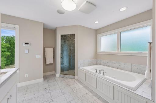 Ultimate relaxation. Enjoy a spa-like primary bathroom complete with premium marble flooring, a large dual vanity with abundant storage, a private water closet, a double linen closet, a jetted soaking tub, and a custom-tiled walk-in shower.