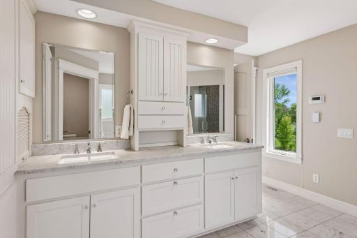 Incredible vanity organization. Features a built-in appliance garage, ample cabinets, and two sinks, all illuminated by recessed lights and a bright window. Bonus: integrated surround sound for your morning playlist!
