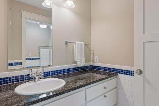 Timeless design meets daily convenience. This bright bathroom coordinates white honeycomb flooring with clean white subway tile walls and a fun blue accent. Includes a built-in linen closet and separate vanity spaces.