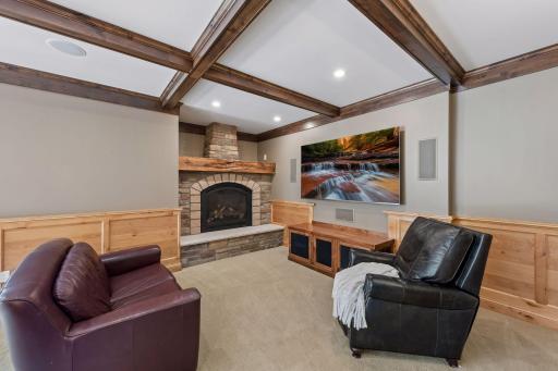 The ultimate spot to unwind! This cozy media lounge features a gorgeous stone gas fireplace, an integrated media bench, and rich knotty pine wainscoting. Overhead, stunning wood beams accent a beautifully crafted coffered ceiling.