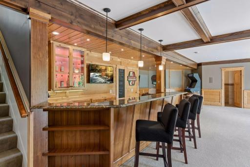 Belly up to the bar! Featuring seating for four, a premium granite counter, & tile floors, this setup is built to host. It features custom pendant & recessed lighting, a lit glass cabinet, & a clever drink specials chalkboard that hides the AV wiring