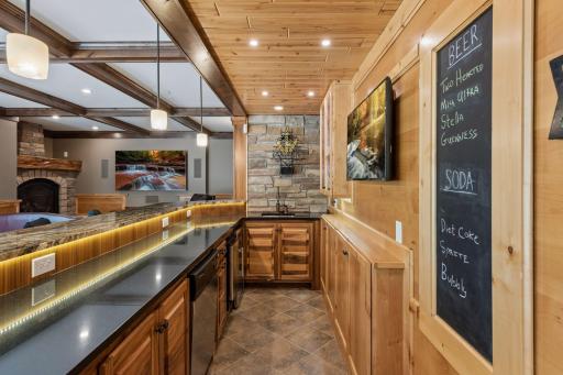 The ultimate host's vantage point! This behind-the-bar view highlights the seamless layout of the durable ceramic tile floor, the premium handmade cabinets, and high-end conveniences like the full dishwasher, ice maker, sink, and beverage fridge.