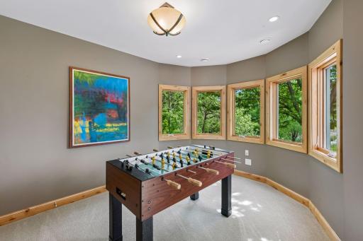 A sun-drenched architectural gem! The lower level of the home's unique turret features a beautiful curved wall of windows that completely floods the space with natural light. Bonus: a highly practical under-stairs storage closet is just steps away.