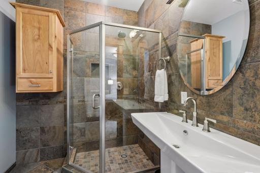 Pure boutique hotel vibes! This stylish private 3/4 ensuite features beautiful ceramic tile floors and walls, pristine built-in storage cabinets, a sleek glass-enclosed shower, and a striking, modern white ceramic trough sink as the centerpiece.