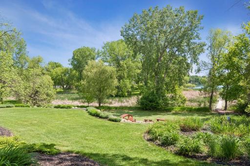 Stunning view of the professionally landscaped yard with mature trees and the beautiful lake.