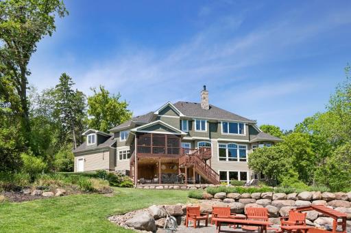 A beautifully manicured lakeside oasis. Admire the impressive tiered stonework and professional landscaping leading down the lawn. The cozy fire pit area comes complete with custom handmade pine furniture included!