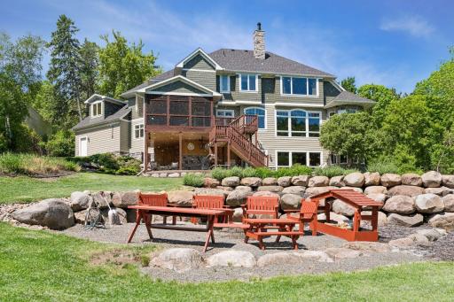 Designed for memorable evenings. This angle captures the impressive tiered stonework and lush lawn. The fire pit serves as the perfect lakeside gathering spot, and the beautiful handmade pine furniture stays for the new owners!
