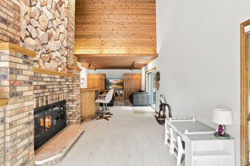 Family room on the other side of the two sided gas burning fireplace. Patio door on the right leads to the side yard.