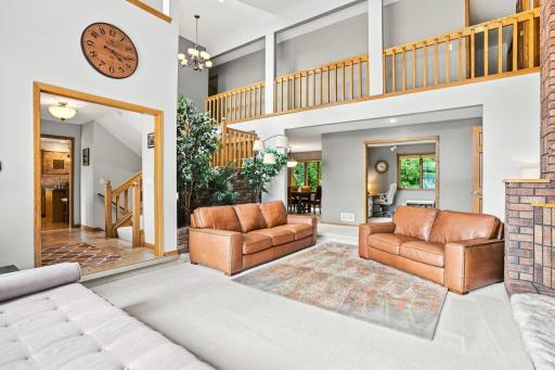 Living room with view of the entry way that leads to the kitchen, stairs to the other levels, dinning area and office