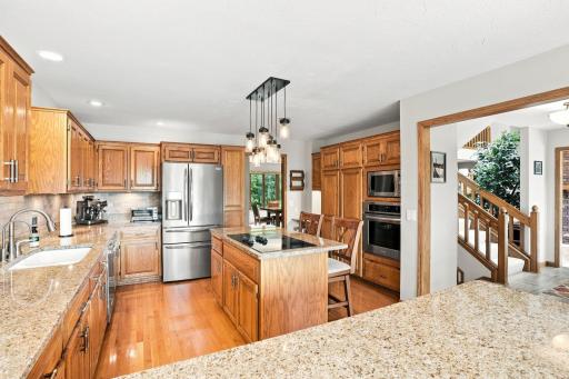 Full kitchen view with built in oven and microwave. On the right is the entry way and stairs leading to the upper and lower levels