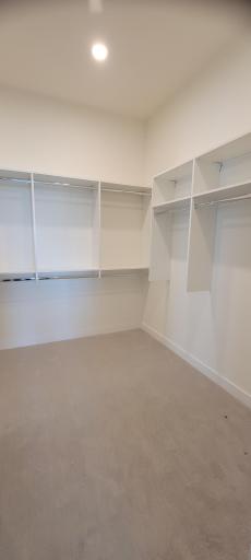 This generous owner's dressing room is sure to house all of your favorite wardrobe pieces utilizing our custom shelving system. Did you know this closet also provides pass-thru access directly into your laundry room?