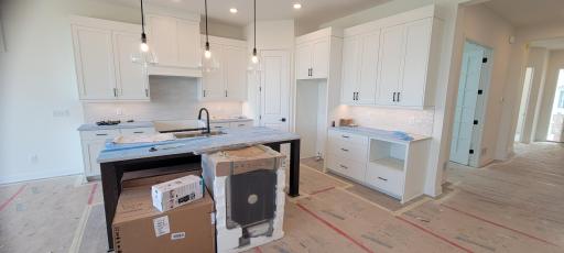 Gourmet kitchen with long center quartz island, ceramic backsplash, elegant task lighting, separate pantry with custom shelving, entertainment coffee bar and abundant natural and designer lighting.
