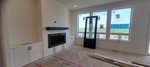 Warm and inviting great room centered around a modern gas fireplace with quartz surround, roll-out craftsman storage mantel, custom cabinetry and bright oversized windows, designed to deliver tons of vitamin c and fresh country air.