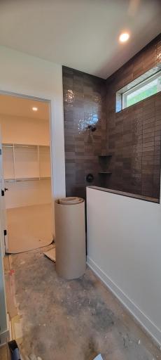Spacious and bright, step-in extra large tiled shower with beautiful glass door and panel creates a fresh and relaxing feel.