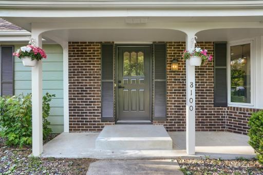 The inviting covered front porch creates a warm and welcoming first impression, blending classic charm with updated style. Framed by stately white columns, rich brick accents, and contrasting black shutters, the entry exudes timeless curb appeal.