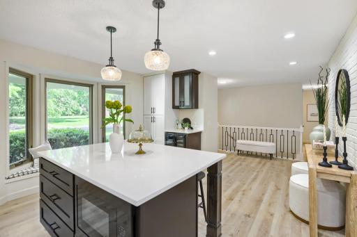 Striking two-tone cabinetry pairs crisp white upper cabinets with rich dark lower cabinetry, creating a sophisticated designer look. Premium black appliances, a double wall oven, custom wood vent hood all add to the beauty of this designer kitchen