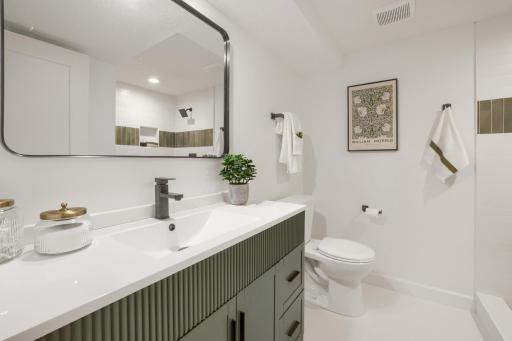 Beautifully remodeled with today's most sought-after finishes, this stylish lower-level bathroom offers both functionality and designer appeal. A contemporary vanity with quartz countertop, designer cabinetry, white tiled floors & updated lighting,